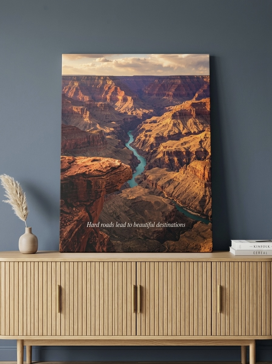 Aerial desert canyon canvas wall art in terracotta and amber tones, displayed above a leather chair in a warm modern reading nook